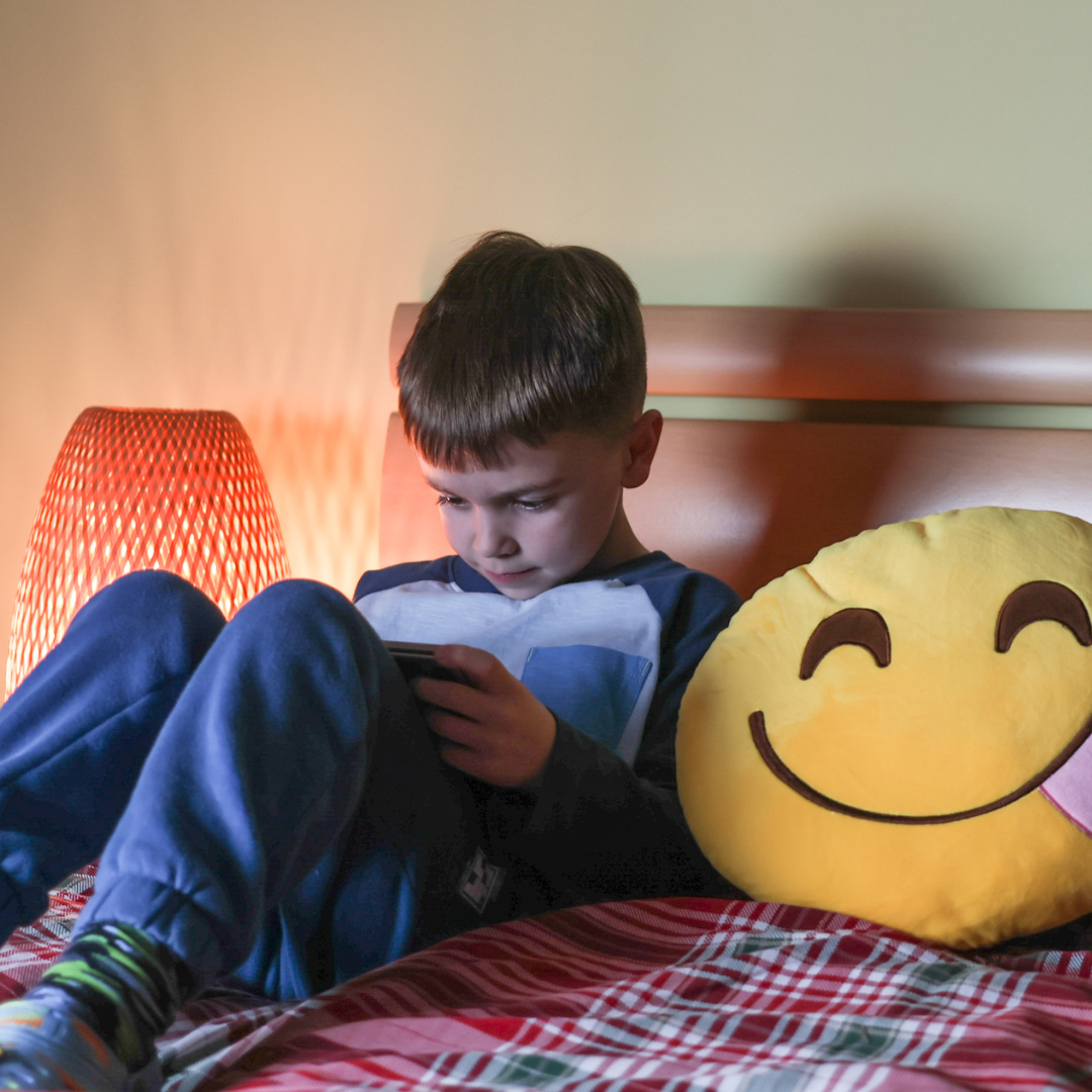 Child watching a tablet while lying on his bed