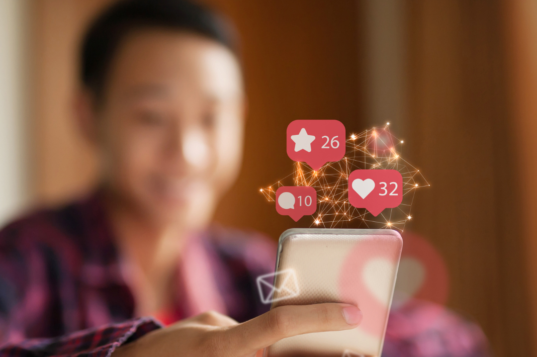 A phone being held and there are hearts, stars and comments on red bubbles